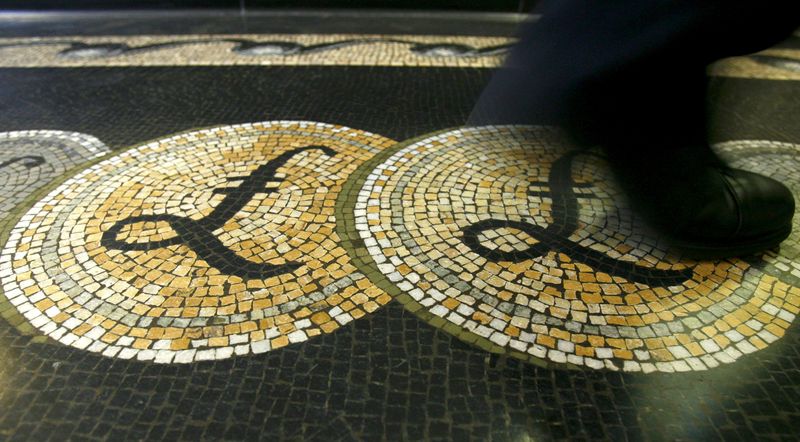 FILE PHOTO: File photograph shows an employee walking over a mosaic depicting pound sterling symbols on the floor of the front hall of the Bank of England in London