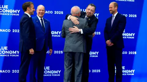 French President Reuters Emmanuel Macron, Prince Albert II of Monaco, Brazilian President Luiz Inacio Lula da Silva, Costa Rico Rodrigo Chavez Robilelis, and Prince William greeting each other in the forum, standing in front of a blue wall with the slogan of the blue economy written on it.